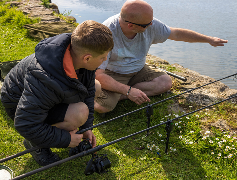 Bailiff teaches a young angler effective angling techniques during a junior angling session.
