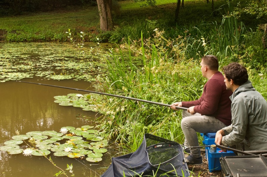 Two men on the riverbank with one rod waiting for a bite