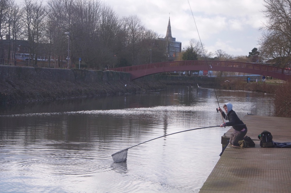 Young person fishing on a canal